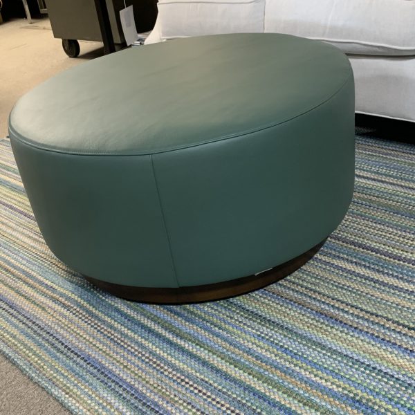 olive green automan over a multicolored braided rug with blues, greens, and yellows.