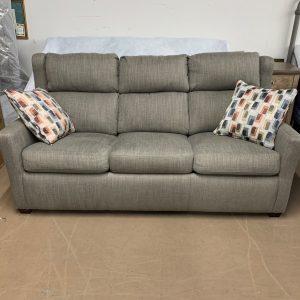 Gray three seater couch in fabric. Two decorative pillows in a geometric design with multiple colors on each end.