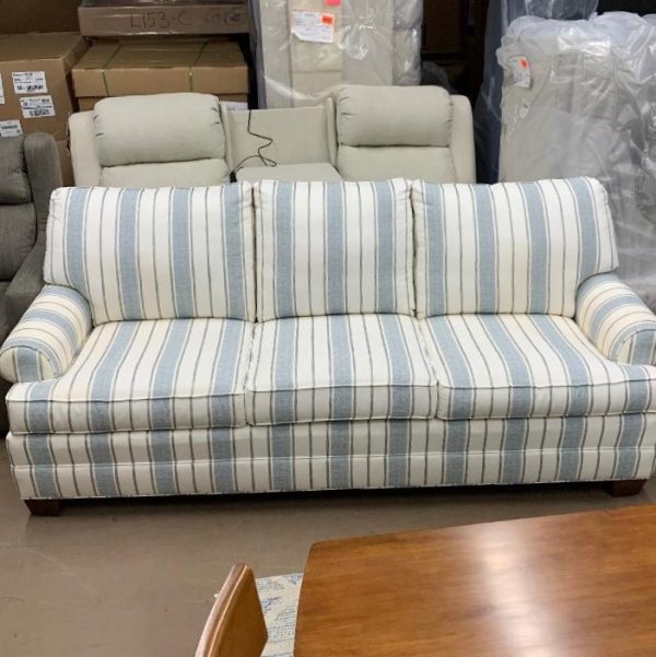 White and light blue striped couch made with fabric. Three seater couch. Recliners in background.