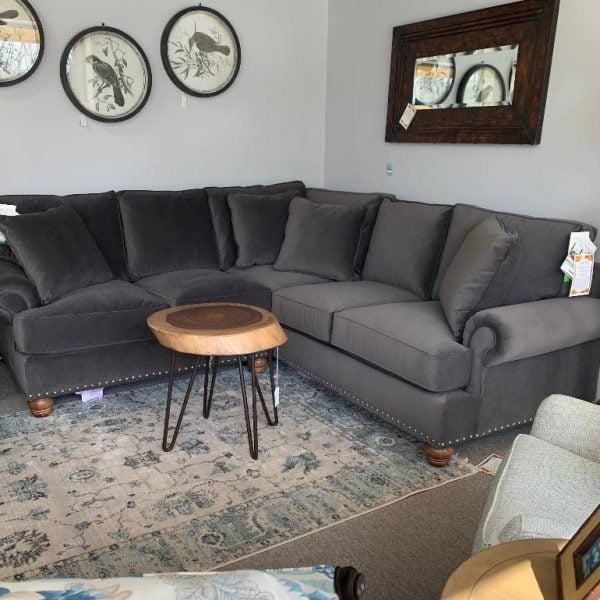 Dark gray sectional couch with a wooded tree trunk like table centered in the middle of sitting area. Blue and white patterned rug underneath.