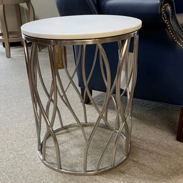 Metal design end table with white marble top. Placed next to black leather chair.